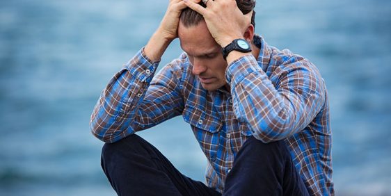 male wearing button up shirt with hands in head