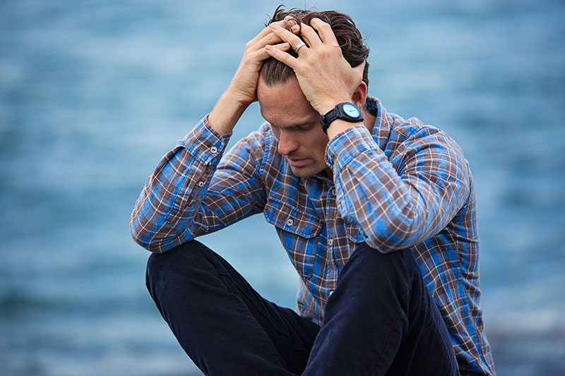 male wearing button up shirt with hands in head