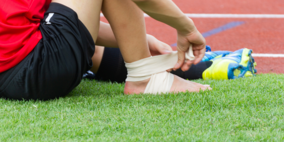 person in black shoes strapping foot with bandage