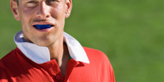 male wearing mouthguard and red jersey on greed background