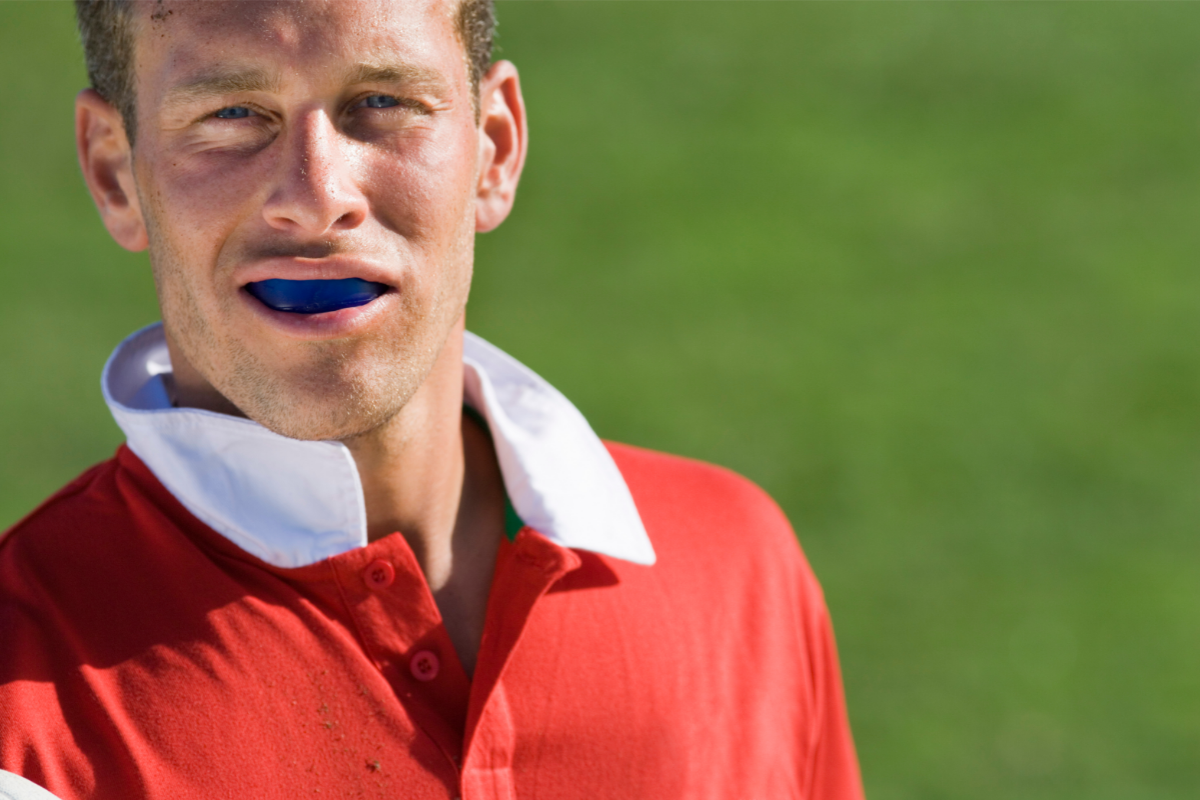 male wearing mouthguard and red jersey on greed background